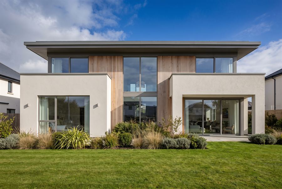 The front elevation of a contemporary two-storey house in pale render and timber.